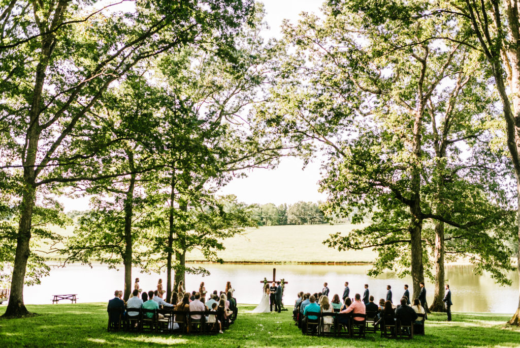 intimate wedding ceremony surrounded by trees with a pond in background